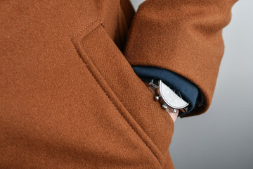 Detail of luxury watch on wrist of business man.Man's hand in the pocket of brown wool coat, casual...