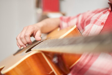 Unrecognizable young man playing guitar at home