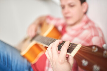 Young hispanic man playing guitar at home