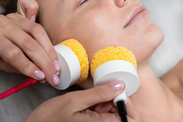 Close-up beautician doctor hand making anti-age face remodel procedure treatment with hardware...