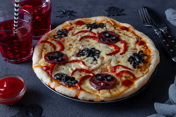 Halloween funny pizza with spiders, Creative idea for Halloween pizza on dark background with drinks and decorations