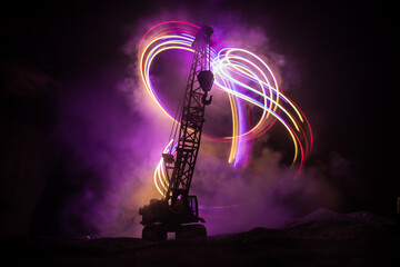 Fototapeta na wymiar Abstract Industrial background with construction crane silhouette over amazing night sky with fog and backlight. Tower crane against the foggy sky at night.