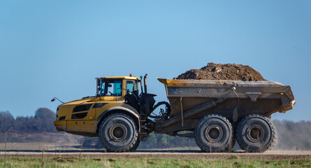 yellow Volvo A40E articulated dump truck earth mover with 25 tonne full payload driving across Salisbury Plain, Wiltshire UK