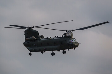 RAF Chinook UH-1 helicopter flying low in a cloudy blue grey and white winter sky on a military exercise, Wiltshire UK