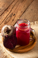 Red beet juice in a glass cup on the wooden table.
