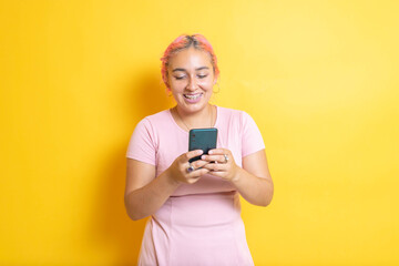 Fototapeta premium Young Mexican student smiling using cell phone. Hispanic sending messages