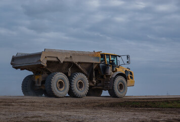yellow Volvo A40E articulated dump truck earth mover driving across Salisbury Plain, Wiltshire UK