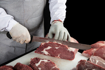 Close up of minced meat pieces and butcher's male hands in special gloves cutting with knife. Meat...