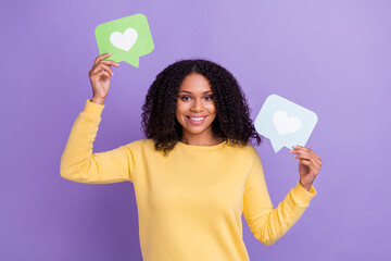 Photo of shiny sweet dark skin woman wear yellow sweater smiling holding heart like signs isolated violet color background