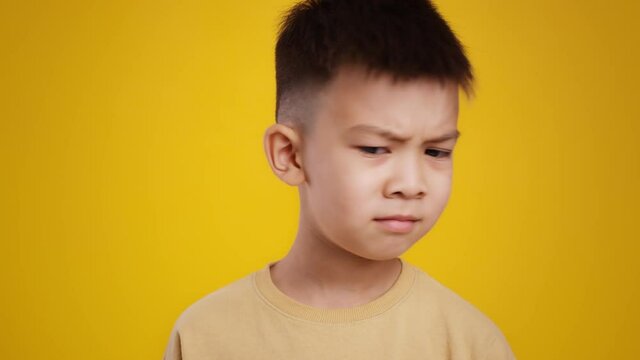 Bad smell concept. Close up portrait little asian boy sniffing and smelling around, feeling annoying disgusting odor