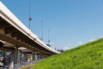 青空を背景に高速道路と土手の緑の斜面
