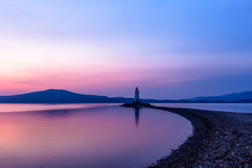 Fototapeta na wymiar The Tokarevsky lighthouse in Vladivostok stands on a deserted spit. Bright sunrise in the sea capital of the Far East.