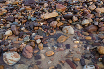 colourful stones and pebbles on the ground with clear water at the beach in Adelaide, South Australia