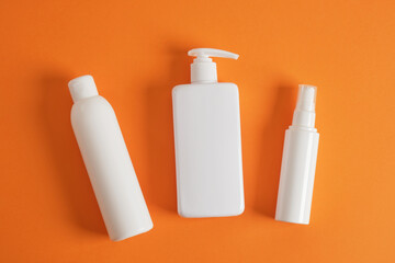 three different blank white bottles on a orange background background