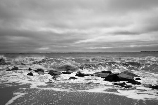 Black and white photo at Vilano Beach, Florida with rocks on the shoreline and whitecaps on the waves