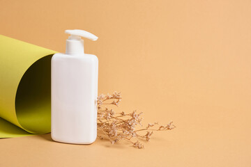 flower and mock up blank white bottle with dispenser for cosmetics on the background of a roll of green paper texture