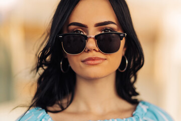 Fototapeta na wymiar Portrait of a beautiful young brunette woman in sunglasses smiling