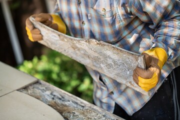 A worker with gloves lays down and dismantles the ceramic tiles of the stairs