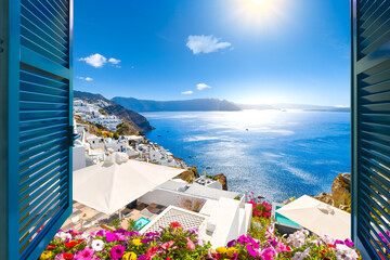 Fototapeta premium View from an open window with blue shutters of the Aegean sea, caldera, coastline and whitewashed town of Oia, Santorini, Greece.