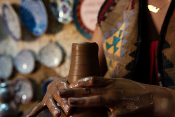 Pottery making, young woman learning to make pottery, a woman trying to shape the material used to make pottery, trying to make a vase out of clay