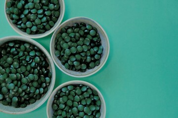 Spirulina algae dry tablets. Spirulina pills in cups . Vegetarian omega three.Plant source of amino acids and omega 3.Omega three alternative source. Super food. 
