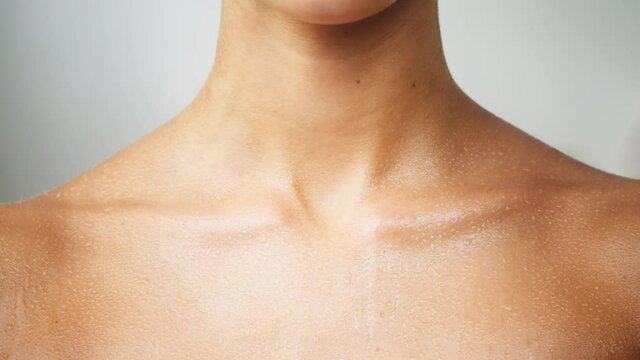 Woman wet clavicles close-up, model with smooth healthy skin after shower. Female shoulders, naked body. Beauty and body care concept. Unrecognizable person with bare neck on white background.