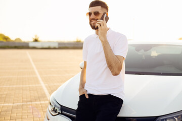 young business man talking on a mobile phone in the city near a white car