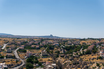 Fototapeta premium Cappadoci, a landscape photo taken from Uchisar castle, houses of the same structure and scattered but impressive architecture of the city, light blue sky and amazing landscape, travel to Turkey