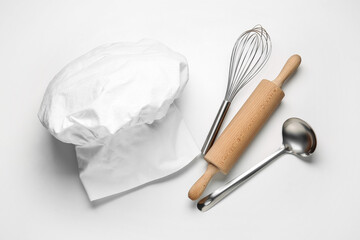 Chef's hat and kitchen utensils on white background