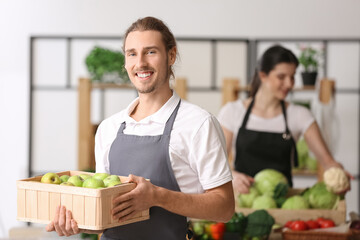 Male seller with fresh apples in market
