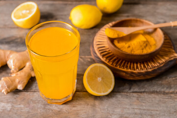 Fototapeta premium Glass of tasty juice with lemon and turmeric on wooden background