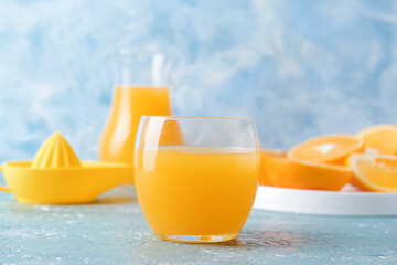 Glass with tasty orange juice on color background