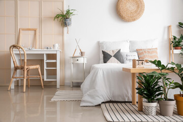 Interior of stylish bedroom with modern workplace and houseplants
