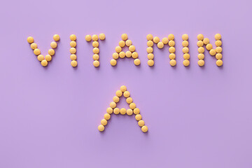Text VITAMIN A made of pills on color background
