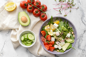 Plate with healthy salad with feta cheese on light background