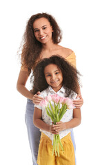 Fototapeta na wymiar African-American little girl with her mother and bouquet of tulips on white background