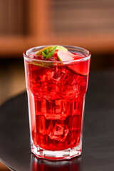 Glass of tasty ice tea with lime on table in room