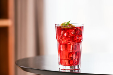 Glass of tasty ice tea with lime on table in room