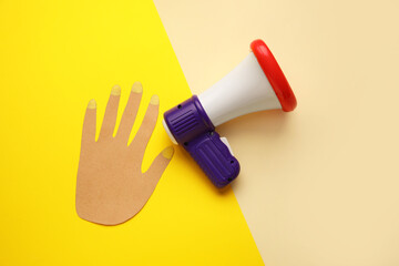 Obraz premium Toy megaphone and paper hand on color background