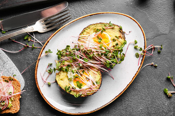 Plate with tasty stuffed avocado and micro green on dark background