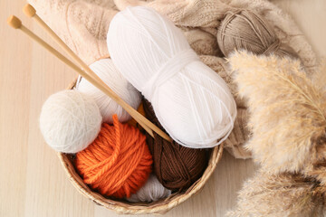 Fototapeta na wymiar Basket with knitting yarn and needles on wooden background