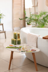 Table with flowers, magazine and candles in bathroom