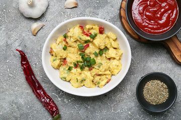 Bowl of tasty chicken curry and ingredients on grunge background