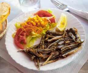 Picture of delicious dish of fried anchovy with tomatoes, corn and lemon..