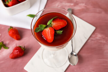 Tasty strawberry panna cotta in glass on color background, closeup