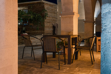 Chairs and table, a modern building and a wooden house standing in the background.