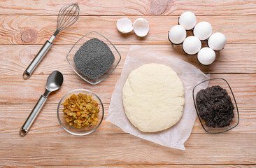 Fresh dough for poppy seed bun and ingredients on wooden background