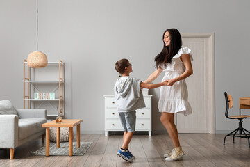 Young woman and her little son dancing at home