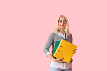Portrait of mature businesswoman with folders on color background