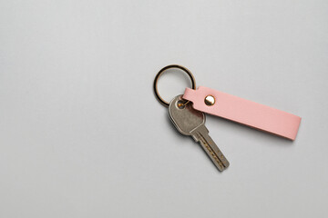 Key with leather keychain on grey background